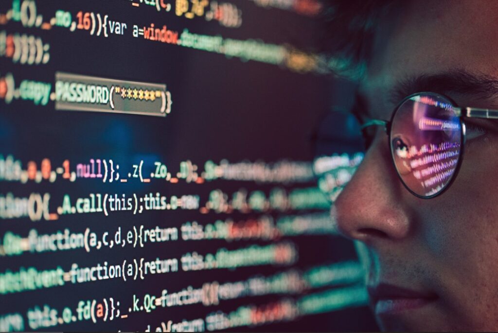 programmer looking at the screen with codes reflected in the glasses 