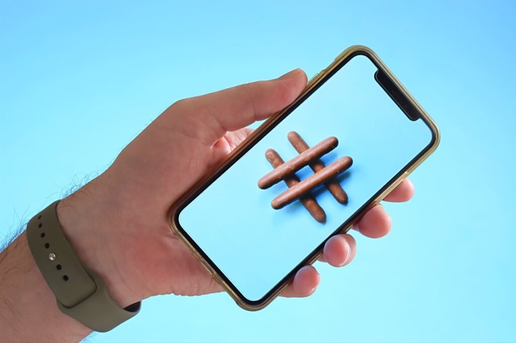 hand holding cell phone with a hashtag in the center of the screen